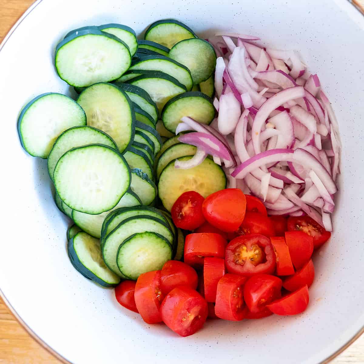 cucumbers, onions and tomatoes in a bowl.