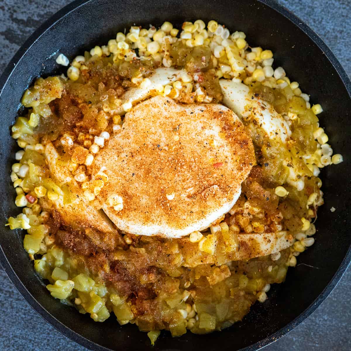 Oaxaca cheese in skillet surrounded by corn and hatch chile.