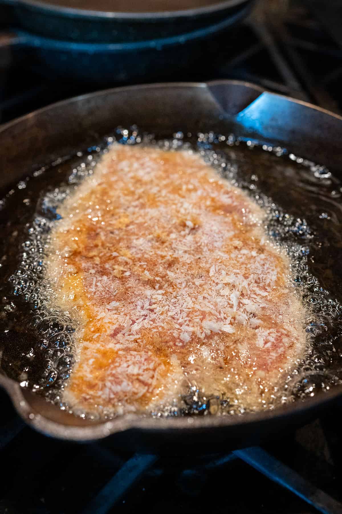 Frying pork schnitzel in gravy.