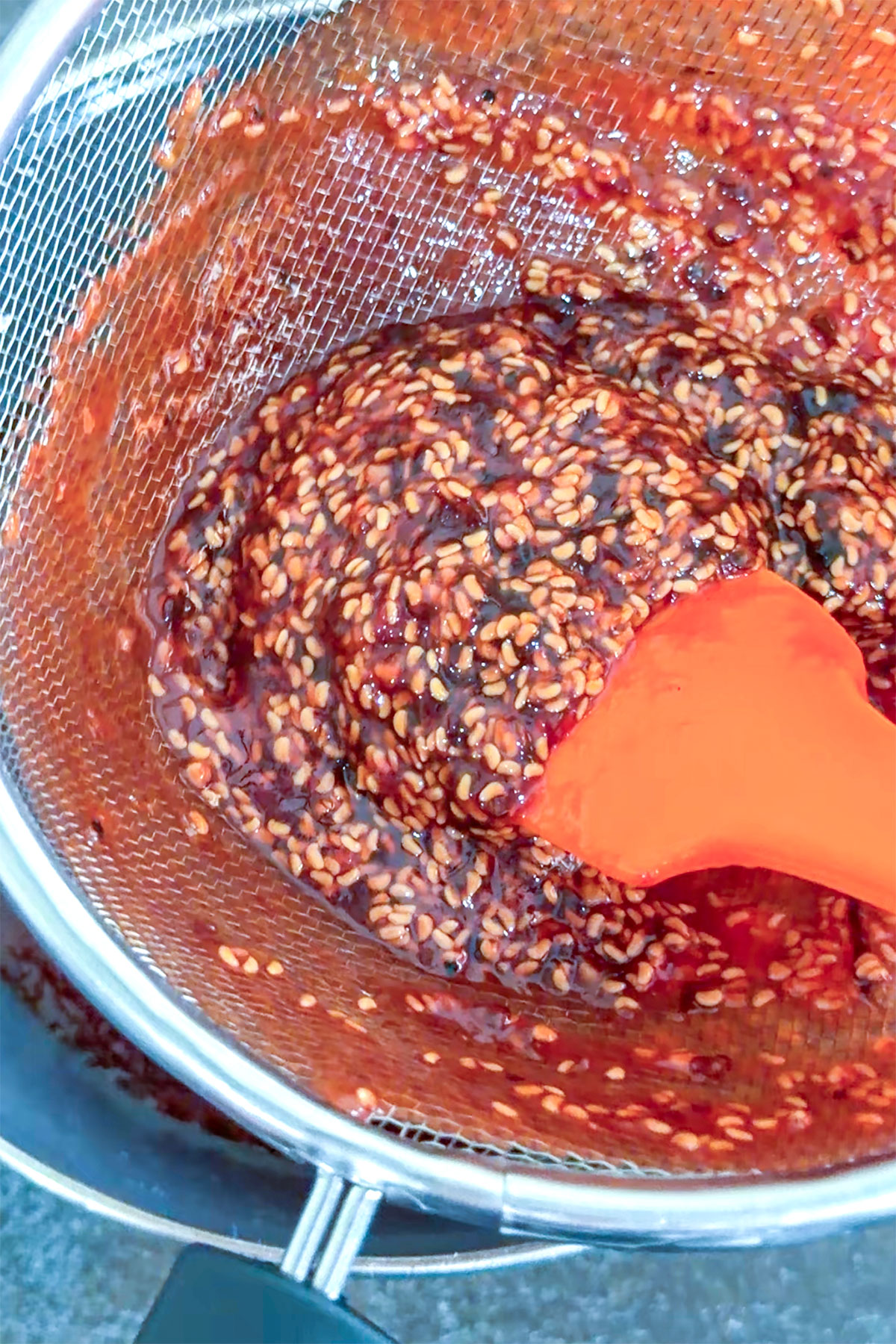 Straining Raspberry Chipotle Sauce to remove seeds.