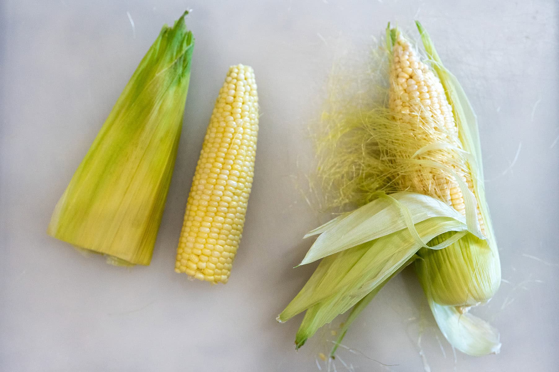 two ears of corn with husk removed.