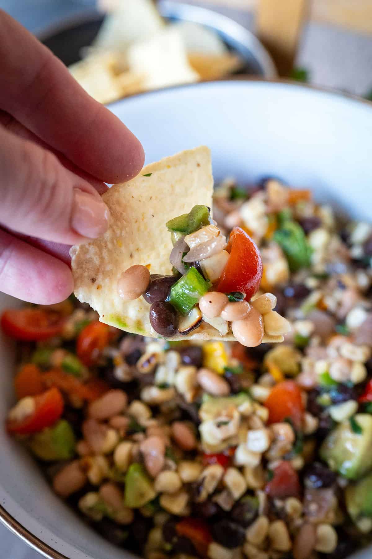 Tortilla chip scooping cowboy caviar dip.